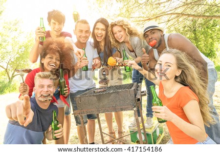 Happy multiracial friends having fun at picnic barbecue garden party - Friendship concept with multiethnic people taking group photo with barbeque grilled food - Warm filter with enhanced sushine halo