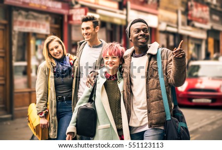 Happy multiracial friends walking on Brick Lane at Shoreditch London - Friendship concept with multicultural young people on winter clothes having fun together - Soft focus with dark contrasted filter