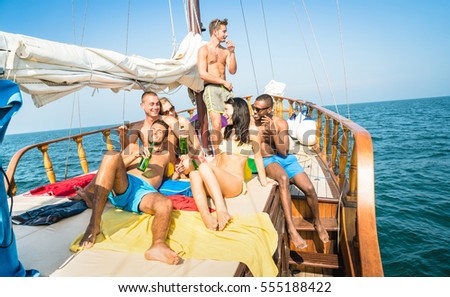 Happy multiracial friends drinking beer and having fun at sail boat party tour - Friendship concept with young multi racial people toasting together on sailboat - Travel lifestyle exclusive location