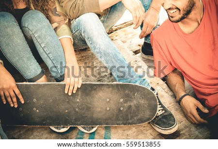 Group of multiracial friends having fun and spending time together at skate board park  - Youth friendship concept with young people sharing skateboard outdoors - Vintage retro desaturated filter