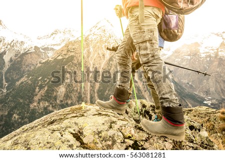 Close up of trekking legs and boots on french alps - Hiker with backpacks and sticks walking on mountain - Wanderlust travel concept with sporty people at excursion in wild nature - Focus on left shoe
