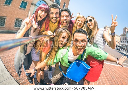 Group of multicultural tourists friends having fun taking selfie and shouting out at old town tour -Travel lifestyle concept with happy people wandering around city landmarks - Vivid saturated filter