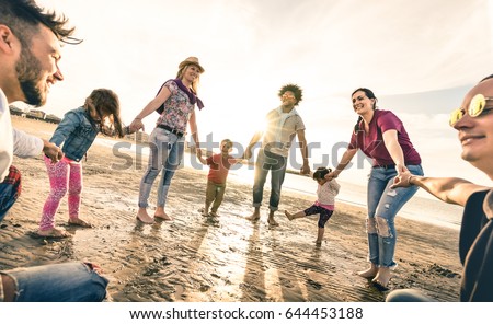 Happy multiracial families round dancing at the beach on ring around the rosy style - Multicultural happiness joy concept with mixed race people having fun outdoor at sunset - Vintage backlight filter