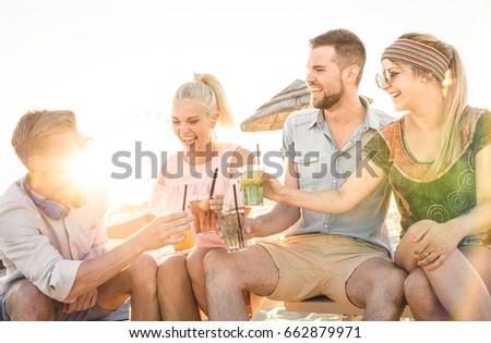 Happy friends group having fun at beach party drinking cocktail at sunset - Summer joy and friendship concept with young people on vacation - Warm sunshine filtered color tone with focus on blond girl