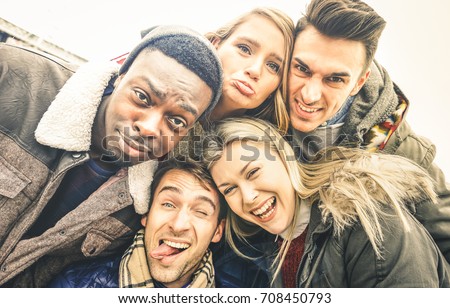 Best friends taking selfie outdoor on autumn winter clothes - Happy youth concept with multiracial people having fun together - Cheer and friendship against racism - Retro contrast desaturated filter