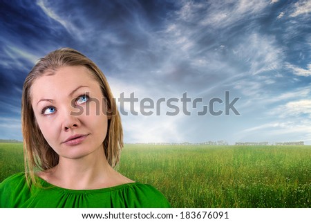 Dreaming beautiful young woman against summer landscape