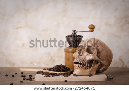 coffee bean on scoop,grinder and human skull on wood background