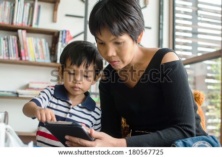 mother teaching son to use tablet
