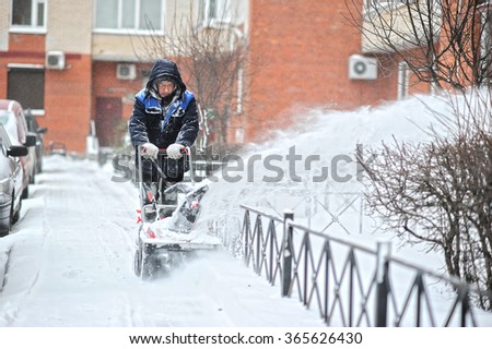ST. PETERSBURG, RUSSIA - JANUARY 12, 2016: a man removes snow in the yard of a multistory building with snow machines