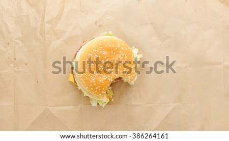 bitten off  burger on paper background. Top view