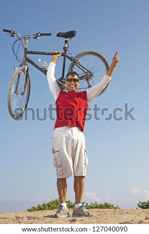 Hispanic male holding up mountain bike in victory holding up number one finger
