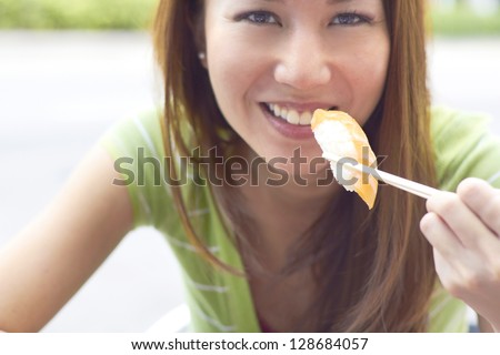 Portrait of a happy Asian woman eating sushi. Horizontal Shot.