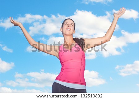 Fit young woman with arms outstretched against cloudy sky. Horizontal Shot.