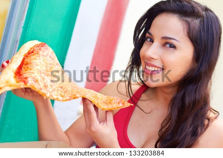 Portrait of a beautiful young woman having a large slice of pizza. Horizontal shot.