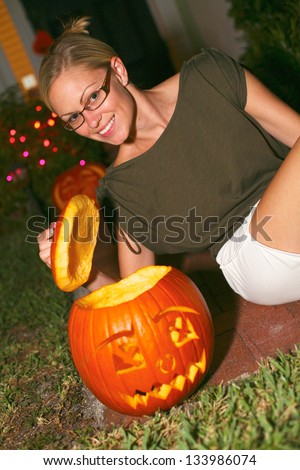 Portrait of happy young woman sitting an anthropomorphic Halloween pumpkin lantern. Vertical shot.