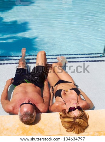 Mature caucasian male and female relaxing in the pool next to each other.