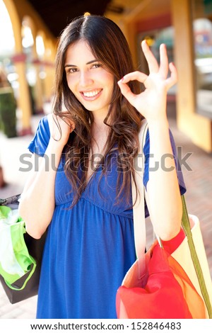 beautiful young latin girl with shopping bags giving okay sign