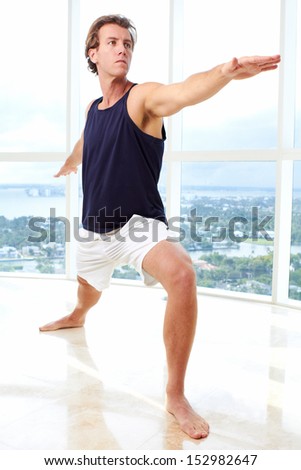 Caucasian male doing yoga warrior pose indoors in high rise apartment