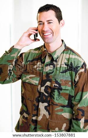 White male in army uniform on cell phone smiling