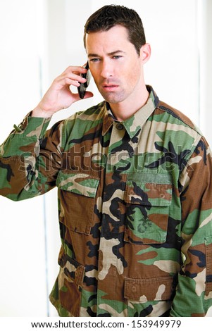 White male in army uniform on cell phone