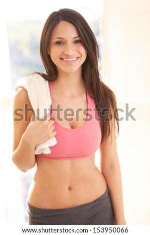 Portrait of fitness young woman smiling with towel on her shoulder. Vertical shot.
