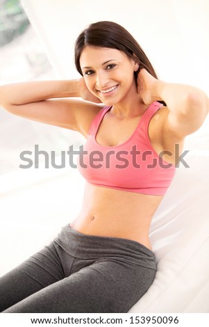 Portrait of young woman smiling while doing physical exercises. Vertical shot.
