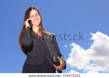 Portrait of a young businesswoman on call holding folder against cloudy sky. Horizontal Shot.