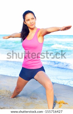 Beautiful female at beach doing yoga warrior pose looking over her right arm for perfect alignment, clearing her mind from the day, stress free