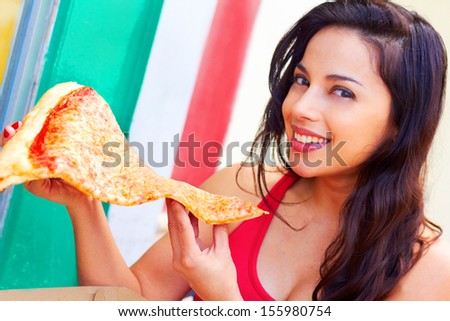 Portrait of a beautiful young woman having a large slice of pizza. Horizontal shot.