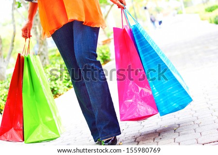 Low section of a woman holding multi colored shopping bags. Horizontal shot.