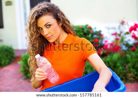 pretty woman holding recycle bin dropping in empty water bottle