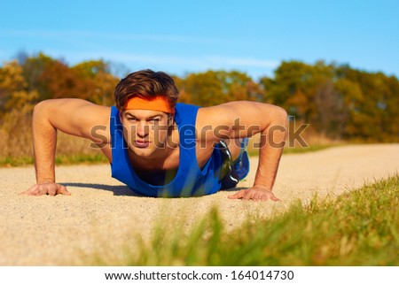 Fitness man doing push ups in nature. Color image, copy space, handsome young man doing push ups for exercise in the grass.Horizontal