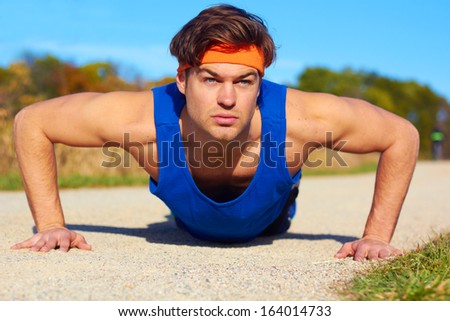 Fitness man doing push ups in nature. Color image, copy space, handsome young man doing push ups for exercise in the grass.Horizontal