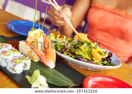 Close up of a Pretty Mixed Race Woman Enjoying A Meal At A Restaurant. African American female enjoying japanese cuisine at a fancy restaurant, using chopstick.