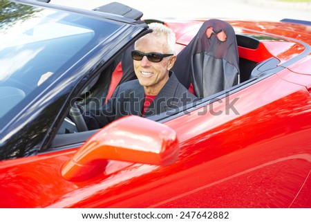 Happy senior man wearing sunglasses while driving red convertible