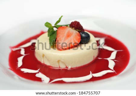 Located on a white plate with dessert with fruit. Around dessert, poured red jam.