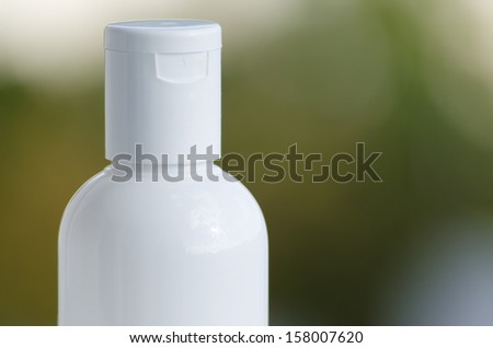 Closeup of white plastic bottle top with no symbols on against a green blurry background in natural light