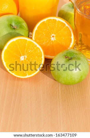Cut oranges, green apples and juice on a wooden table