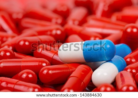 Blue and white pills on background of red pills