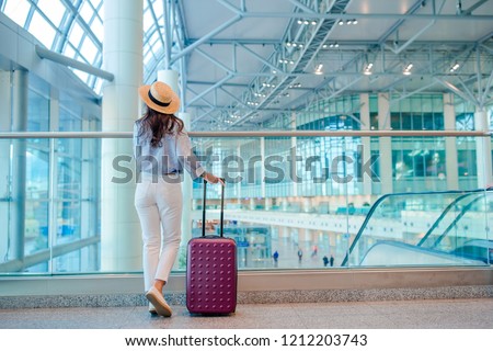 Young woman in hat with baggage in international airport. Airline passenger in an airport lounge waiting for flight aircraft