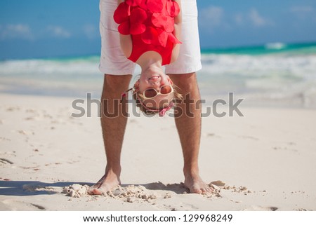Father holding his happy smiling daughter upside down having beach fun