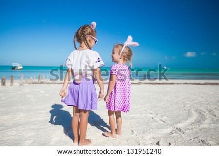 Two little  cute girls in easter ears have fun on the exotic beach