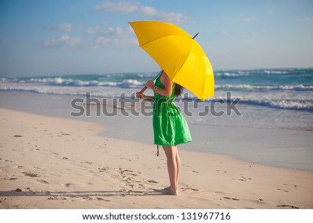 young woman with yellow umbrella on the beach
