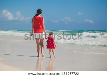 Back view of mother and daughter walking on beach