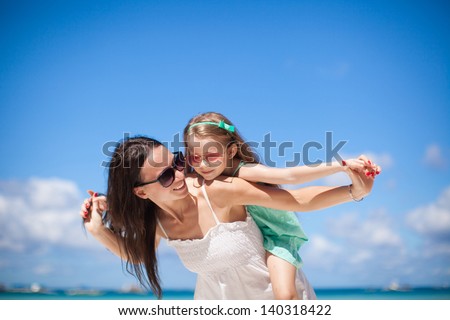 Young beautiful mother and her adorable little daughter at tropical beach