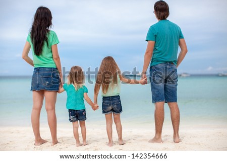 Back view of beautiful family with two kids at exotic beach