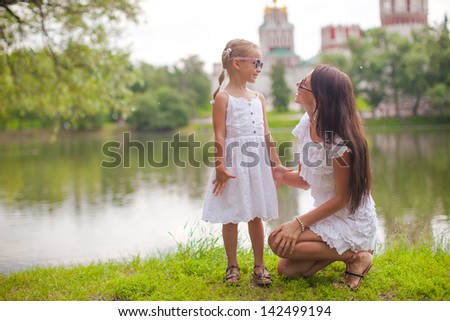 Young mother and her daughter having fun near the lake