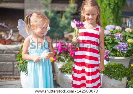 Smily little girls in a country yard with flowers in their hands