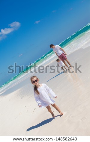 Funny older daughter in the foreground and dad with youngest daughter in the background on the beach