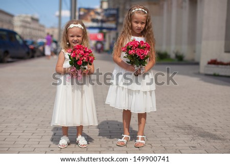 Two charming sisters with beautiful bouquets of roses in his hands go to the wedding